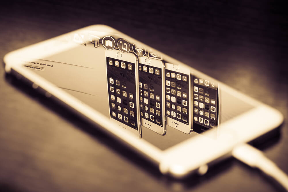 Smartfon odbijający się w ekranie tabletu, tworząc iluzję wielokrotnej ekspozycji.