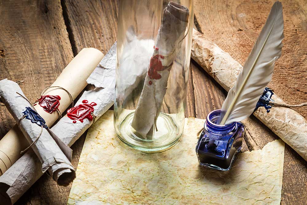 Zwój pergaminu w szklanej butelce na drewnianym stole, obok pióro w kałamarzu z atramentem i kilka zwojów z pieczęciami wosku.