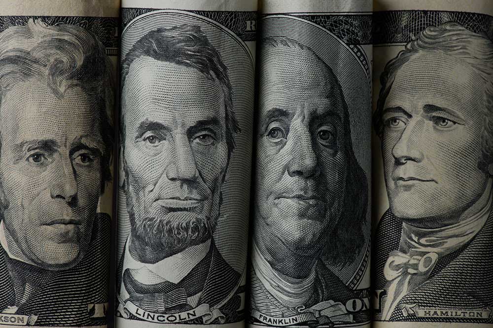 Rolowane banknoty dolarowe z wizerunkami amerykańskich mężów stanu.