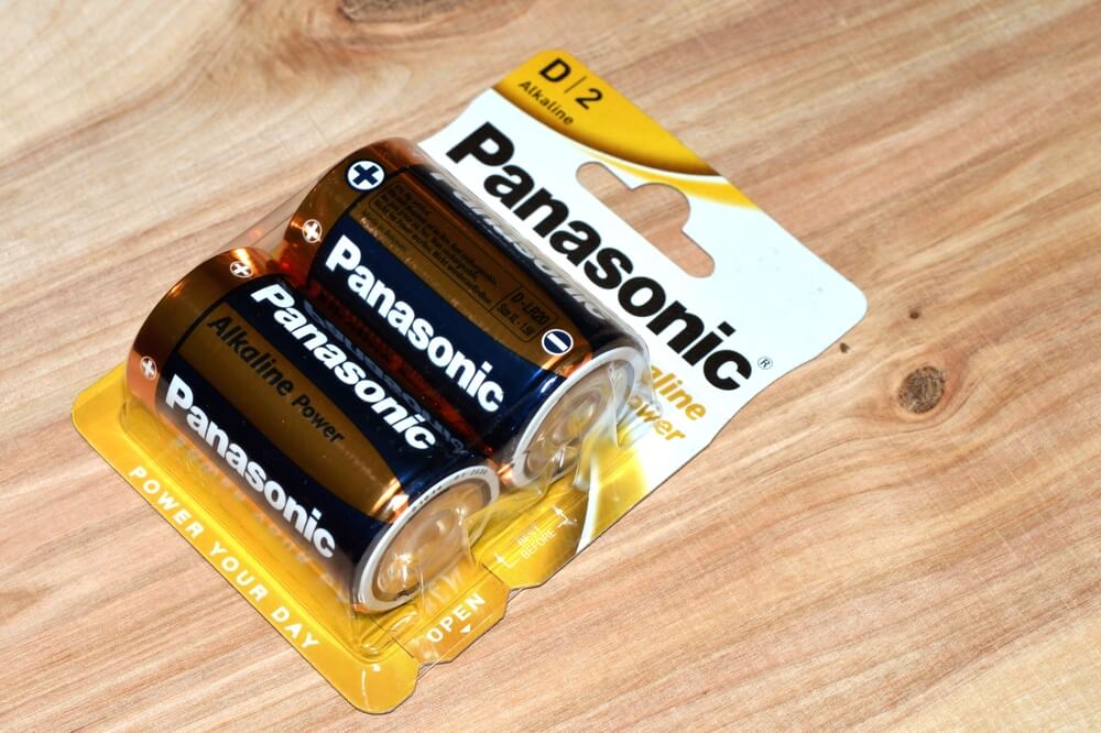 Opakowanie dwóch baterii alkalicznych Panasonic D/2 na drewnianym tle.