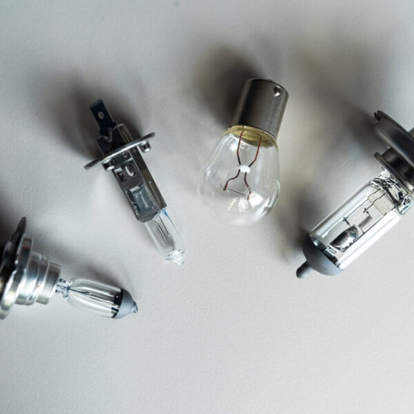 Cztery różne rodzaje żarówek samochodowych leżące na białym tle, w tym żarówki halogenowe i klasyczne.