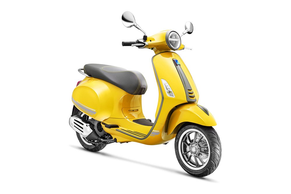 Żółty skuter Vespa na białym tle.