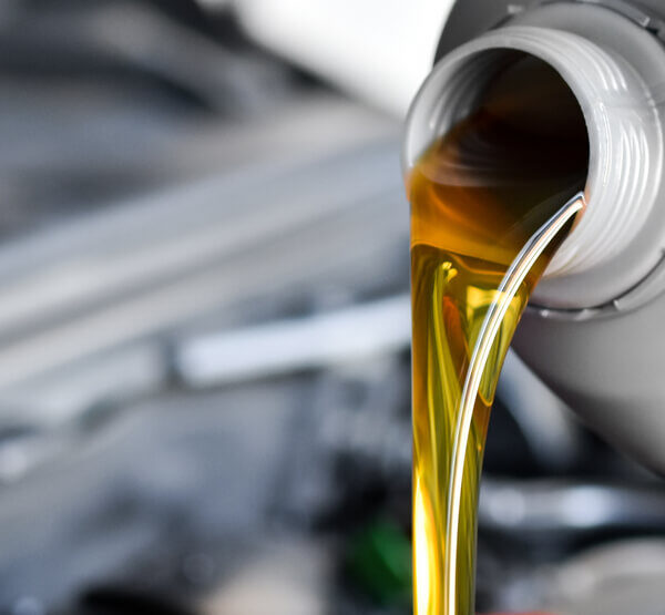 Olejek silnikowy wylewany z plastikowej butelki do wnętrza samochodu.