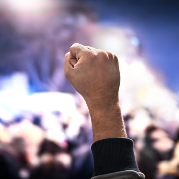 Uniesiona pięść na tle tłumu ludzi podczas demonstracji nocą.