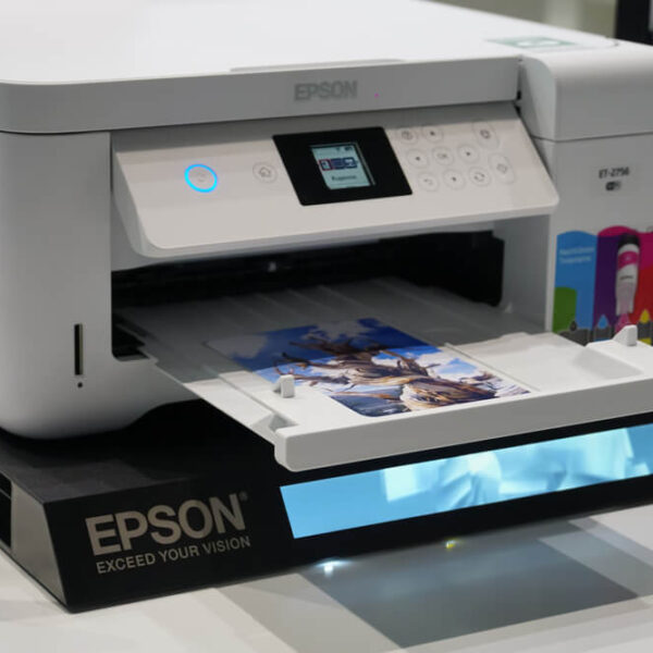 Drukarka Epson z serii ET-2756 podczas drukowania kolorowego zdjęcia, z kolorowymi tuszami widocznymi po prawej stronie.