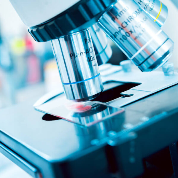 Mikroskop laboratoryjny z bliska, z miejscem na szkiełko pod powiększoną soczewką obiektywu.
