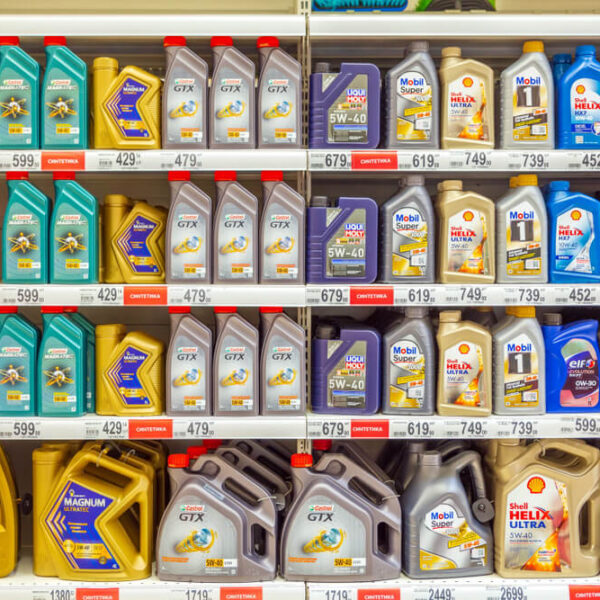 Półka w sklepie z różnymi markami olejów silnikowych w pojemnikach.